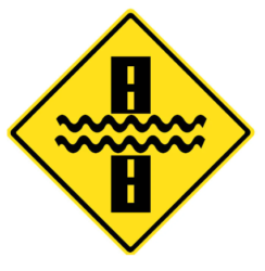 There may be water flowing over the road warning sign for G1 exams and tests preparation on CanDriveHub